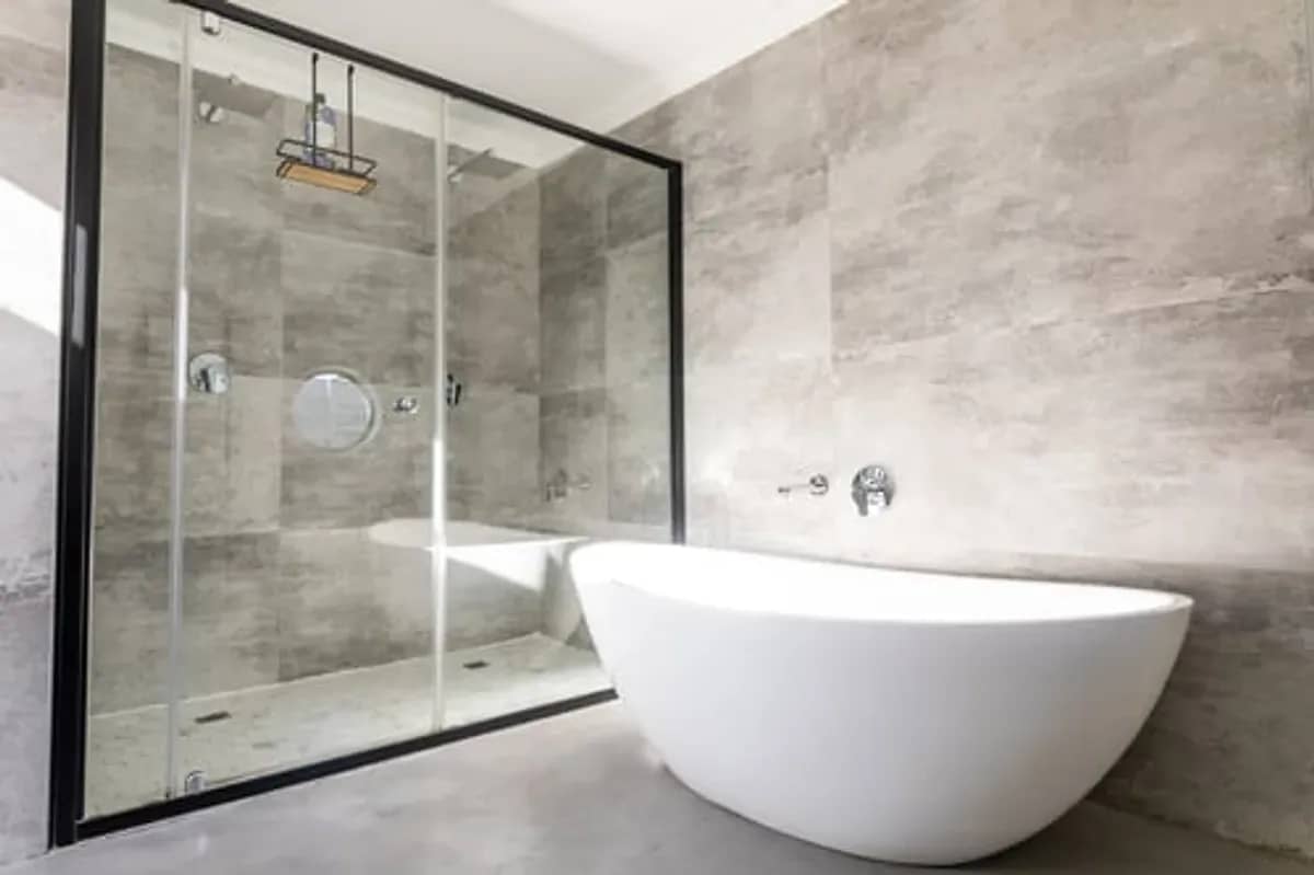 Renovated bathroom with freestanding soaking tub and frameless glass shower enclosure
