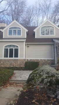 Completed vinyl siding installation with stone veneer front and arched windows on a home in Stamford, CT