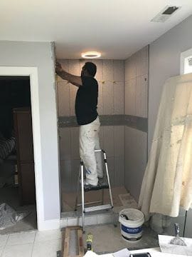 Craftsman installing large-format wall tile in a walk-in shower during a bathroom remodel in Stamford, CT