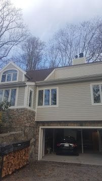 Exterior remodel with new siding, garage entry and stone retaining wall in Fairfield County, CT